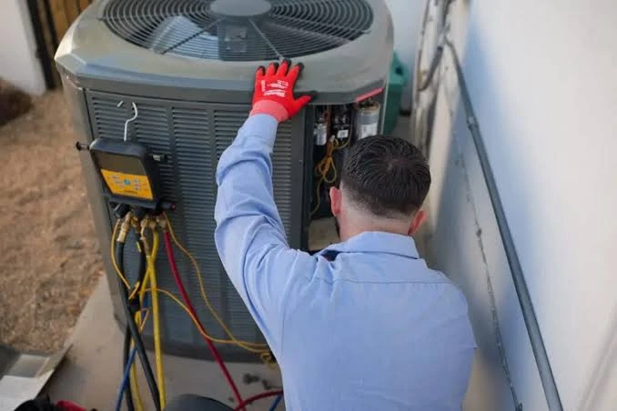 Technician checking the wiring of an outdoor HVAC condenser