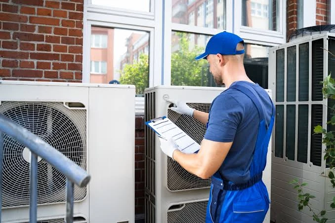 Technician inspecting outdoor HVAC equipment with a clipboard